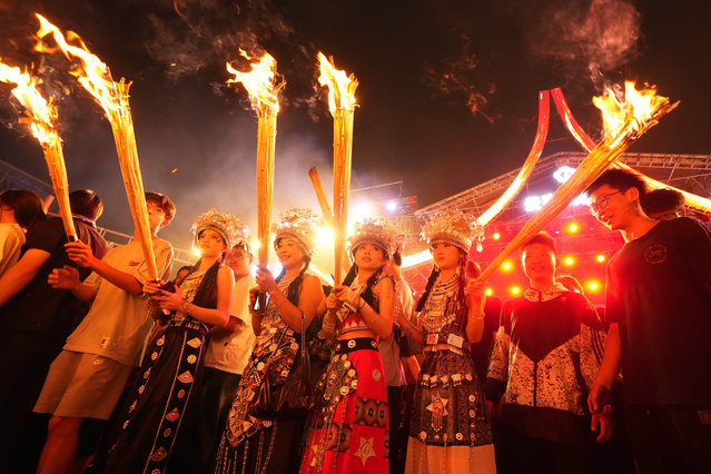 Tourists and local residents hold burning torches to celebrate the Torch Festival at Yunnan Nationalities Village on July 19, 2025 in Kunming, Yunnan Province of China. (Photo by Liu Ranyang/China News Service/VCG via Getty Images)
