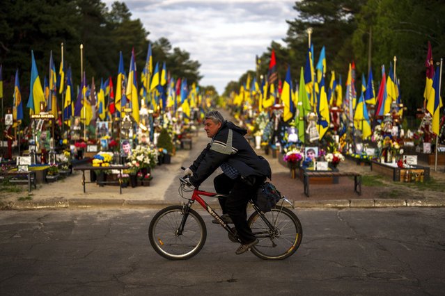 A man rides a bicycle past the tombs of Ukrainian soldiers killed during the war, at Lisove cemetery in Kyiv, Ukraine, Tuesday, April 23, 2024. (Photo by Francisco Seco/AP Photo)