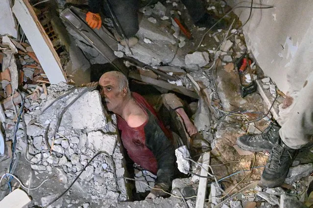 A man trapped in rubble reacts while debris is removed to work on his rescue in Hatay on February 7, 2023, a day after a 7,8-magnitude earthquake struck the country's southeast. Rescuers in Turkey and Syria braved frigid weather, aftershocks and collapsing buildings, as they dug for survivors buried by an earthquake that killed more than 5,000 people. Up to 23 million people could be affected by the massive earthquake that has killed thousands in Turkey and Syria, the WHO warned on Tuesday, promising long-term assistance. (Photo by Bulent Kilic/AFP Photo)