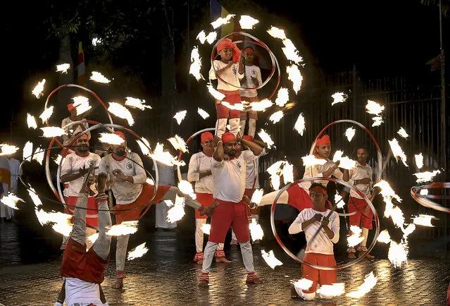 In this photograph taken on August 3, 2020, fire-dancers perform in front of the historic Buddhist Temple of the Tooth, as they take part in a procession during the Esala Perahera festival in the ancient hill capital of Kandy, some 116 km from Colombo. Esala Perahera festival, which usually draws thousands of spectators every year, took place with no spectator insight due restrictions for the coronavirus pandemic. (Photo by Ishara S. Kodikara/AFP Photo)