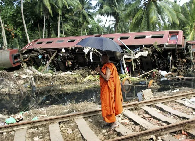 A Buddhist monk looks at a wrecked carriage after an entire train was destroyed by Sunday's tsunami in the town of Paraliya, south of Colombo in this December 30, 2004 file photo. (Photo by Kieran Doherty/Reuters)