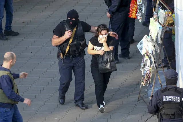 Georgian police officers escorts a woman who escaped from a bank where an armed assailant has taken several people hostage, in the town of Zugdidi in western Georgia, Wednesday, October 21, 2020. The Georgian Interior Ministry didn't immediately say how many people have been taken hostage in the town of Zugdidi in western Georgia, or what demands the assailant has made. Police sealed off the area and launched an operation “to neutralize the assailant”, the ministry said in a statement. (Photo by Zurab Tsertsvadze/AP Photo)