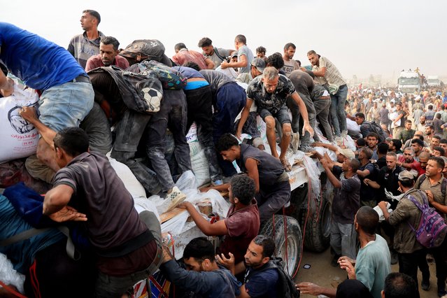 Palestinians scramble to collect aid supplies from trucks that entered through Israel, in Khan Younis, southern Gaza Strip, on August 12, 2025. (Photo by Hatem Khaled/Reuters)