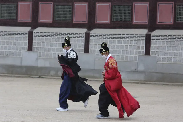 People wearing face masks to help protect against the spread of the coronavirus run during rain at the Gyeongbok Palace in Seoul, South Korea, Sunday, November 1, 2020. (Photo by Ahn Young-joon/AP Photo)