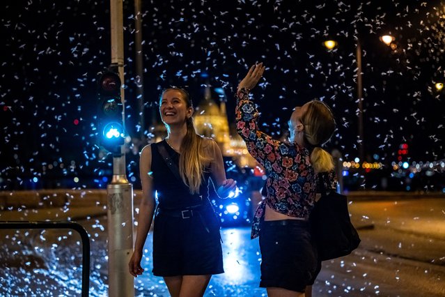 Pedestrians watch the swarming mayflies near the Danube river in Budapest, Hungary, on July 26, 2025. (Photo by Marton Monus/Reuters)