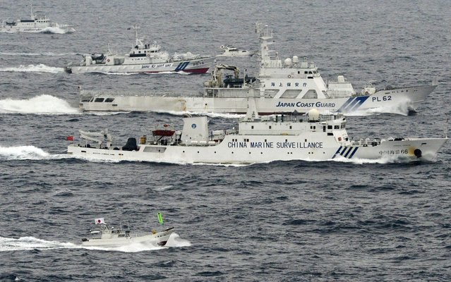 A Chinese marine surveillance ship Haijian (center) cruises next to Japanese coast guard ships in the East China Sea, near islands known as the Senkakus in Japan and the Diaoyus in China, on April 23, 2013. Japan's prime minister says Tokyo will respond with “force” if China lands on islands at the center of a dispute between the two countries. Shinzo Abe's comments on April 23 came after eight state-owned Chinese ships sailed near East China Sea islands that both countries claim. In response, Tokyo summoned the Chinese ambassador to Japan. The warning from Abe is the most explicit warning to China since he took power in December. A flotilla of 10 fishing boats carrying Japanese activists was also reported to be in the area, as well as the Japanese coast guard. The latest spike in tensions comes after 170 Japanese lawmakers on April 23 visited the controversial Yasukuni war shrine in Tokyo, a symbol of Japan's imperialist past. That visit has angered China, which called it an “attempt to deny Japan's history of aggression”. (Photo by AP Photo/Kyodo)