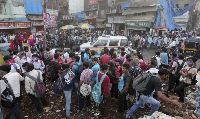 A police vehicle patrols as migrant workers wait for work in Mumbai, India, Monday, November 23, 2020. India has more than 9 million cases of coronavirus, second behind the United States. (Photo by Rafiq Maqbool/AP Photo)