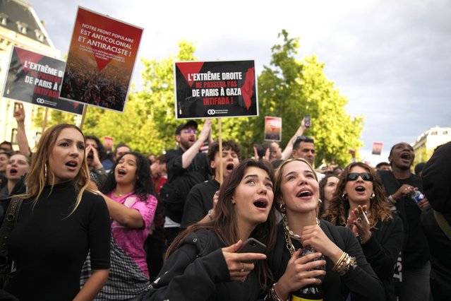 French voters react to the projected results of the second round of legislative elections, near Republique Plaza in Paris, July 7, 2024. (Photo by Christophe Ena/AP Photo)