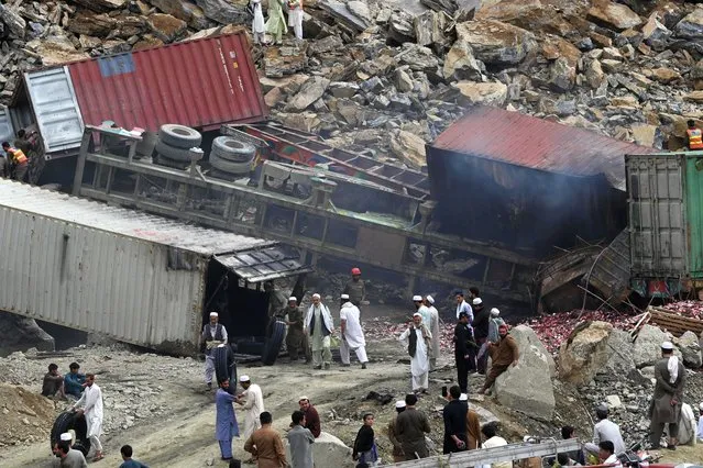 People gather next to wrecked trucks following a landside near Pakistan's Torkham border town on April 18, 2023. At least two people were killed and eight injured in a massive pre-dawn landslide that buried dozens of trucks waiting to cross from Pakistan to Afghanistan, officials said on April 18. (Photo by Abdul Majeed/AFP Photo)