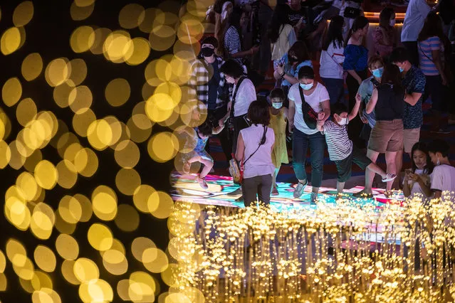 People visit light show to celebrate Christmas and New Year at Central World Department Store in downtown during New Year's Eve on December 31, 2020 in Bangkok, Thailand. Thailand welcomed the new year under a cloud of uncertainty, as sporadic outbreaks of the Covid-19 virus in clusters around the country worried both the public and health experts. (Photo by Sirachai Arunrugstichai/Getty Images)