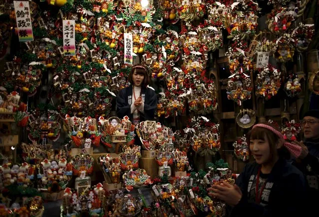 Women promote selling rakes, known as "kumade", decorated with imitation gold coins and other objects during the Tori-no-Ichi fair at Ohtori shrine in downtown Tokyo, Japan, November 29, 2015. (Photo by Issei Kato/Reuters)