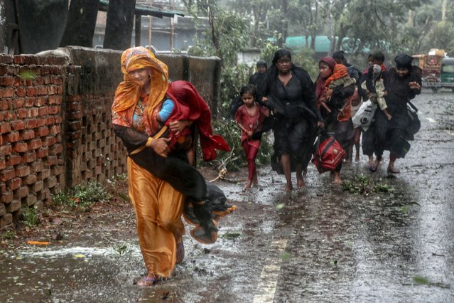 People move from their homes to take shelter in the nearest cyclone shelter at Shah Porir Dwip during the landfall of cyclone Mocha in Teknaf, Bangladesh on May 14, 2023. (Photo by Jibon Ahmed/Reuters)