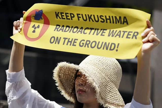 One of protesters holds a banner during a rally outside Tokyo Electric Power Company Holdings (TEPCO) headquarters building Tuesday, May 16, 2023, in Tokyo. Dozens of anti-nuclear activists gathered outside of the Tokyo utility operating a tsunami-wrecked Fukushima nuclear power plant and demanded Japan scrap its plan to start releasing into sea massive stockpile of treated but still radioactive water. (Photo by Eugene Hoshiko/AP Photo)
