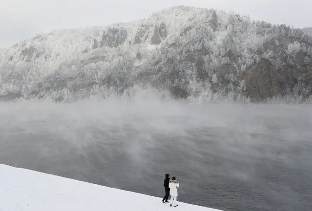 A couple stands on an embankment of the Yenisei River, covered in a frosty fog, with the air temperature at about minus 22 degrees Celsius (minus 7.6 degrees Fahrenheit), in the Siberian town of Divnogorsk near Krasnoyarsk, Russia, November 22, 2015. (Photo by Ilya Naymushin/Reuters)
