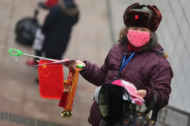 A vendor wears mask to sell national flag and selfie stick at Tiananmen Square during a haze day in Beijing city, China, 08 December 2015. Beijing has issued its first red alert for air pollution under a four-tier emergency response system created in October 2013. The red alert which is the most serious level for Air Quality Index (AQI), last from 7 a.m. on 08 December to 12 a.m. on 10 December. (Photo by Wu Hong/EPA)