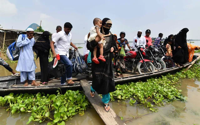 An Indian villager steps off a boat as she carries her child in flood- affected Ashigarh village in Morigoan district, in India' s northeastern state of Assam, on July 6, 2018. Heavy monsoon rains bring floods to parts of northeastern India each year, affecting the lives of millions of people. (Photo by Biju Boro/AFP Photo)