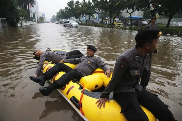 Policemen rest on an inflatable raft at the flooded Kelapa Gading business district in Jakarta, January 23, 2015. (Photo by Reuters/Beawiharta)