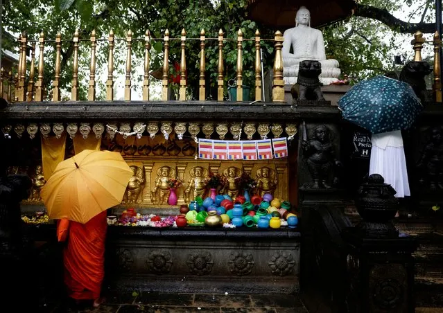 A Buddhist nun worships in front of a statue of Buddha in heavy rain on Vesak day to commemorate the birth, enlightenment and death of Buddha, at Kelaniya Buddhist temple, in Colombo, Sri Lanka on May 5, 2023. (Photo by Dinuka Liyanawatte/Reuters)