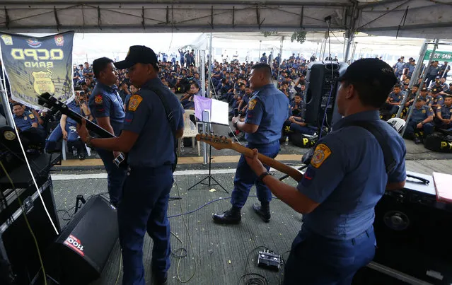 Riot police are entertained by a police band near the venue in anticipation of a big rally to coincide with the third State of the Nation Address of President Rodrigo Duterte Monday, July 23, 2018 in suburban Quezon city northeast of Manila, Philippines. (Photo by Bullit Marquez/AP Photo)