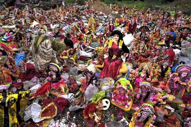 A woman searches for reusable material amid idols of Hindu goddess Dashama left by devotees on the banks of River Sabarmati in Ahmedabad, India, Thursday, July 27, 2023. Every year Hindu devotees in this western state of Gujarat immerse the idols of goddess Dashama in water bodies after worship marking the end of the ten-days long Dashama festival. (Photo by Ajit Solanki/AP Photo)