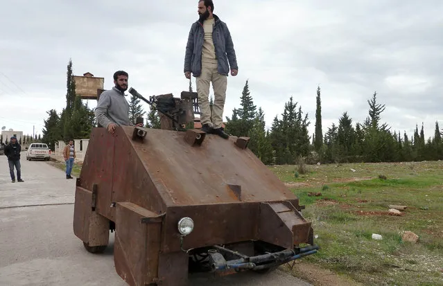 Syrian rebels stand atop Sham II, a homemade armoured vehicle made by the rebels' Al-Ansar brigade, in Bishqatin, 4 kms west of Aleppo, on December 8, 2012. The Sham II, which was cobbled together from the chassis of an old diesel car and parts salvaged from a junkyard in under a month, uses a controller from a Sony Playstation games console to aim a roof-mounted machine gun. Inside the rusting steel panels a crew of two sit side-by-side in front of flatscreen TV's mounted on the wall. Sham II, named after ancient Syria, touted by rebels as “100 percent made in Syria”. (Photo by Herve Bar/AFP Photo)