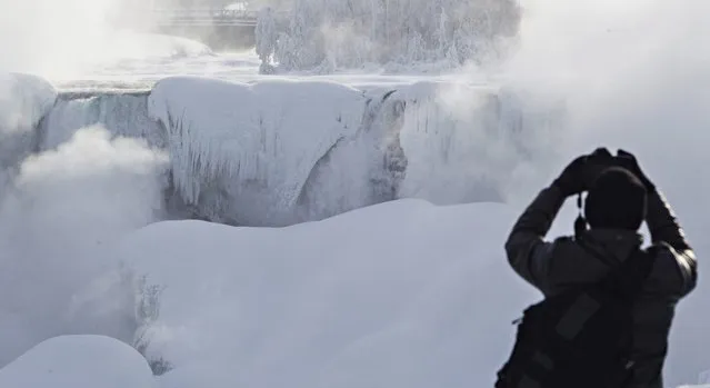 A man photographs ice masses formed around the American Falls as seen from Niagara Falls, Ontario, Canada, Thursday, February 19, 2015. (Photo by Aaron Lynett/AP Photo/The Canadian Press)