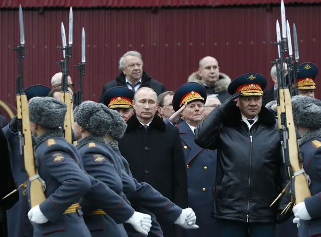 Russian President Vladimir Putin (C) and Defence Minister Sergei Shoigu (R, front row) watch honor guards pass by as they attend a wreath laying ceremony to mark the Defender of the Fatherland Day at the Tomb of the Unknown Soldier by the Kremlin walls in central Moscow February 23, 2015. (Photo by Sergei Karpukhin/Reuters)