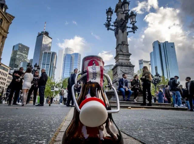 An empty beer bottle stands in front of the buildings of the banking district in Frankfurt, Germany, Friday, May 21, 2021. All people gathering on the square for drinks and food left when the police started checking if they are abiding by the coronavirus restrictions. (Photo by Michael Probst/AP Photo)