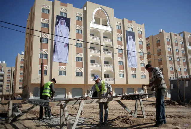 Palestinian laborers work on the second phase of the Qatari-funded Hamad City housing complex in Khan Younis, southern Gaza Strip, Saturday, January 16, 2016. More than 1,000 Palestinian families have taken possession of new apartments in part of the large housing project that sits on dunes that were part of the former Jewish settlement of Gush Katif. (Photo by Khalil Hamra/AP Photo)