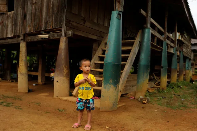 A boy stands in front of a house built on bombs dropped by the U.S. Air Force planes during the Vietnam War, in the village of Ban Napia in Xieng Khouang province, Laos September 3, 2016. (Photo by Jorge Silva/Reuters)