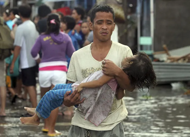 A father carries the lifeless body of his daughter on the way to the morgue after super typhoon Haiyan hit Tacloban City in Leyte province, central Philippines November 10, 2013. (Photo by Nino Jesus Orbeta/Reuters/Philippine Daily Inquirer)