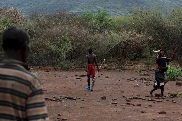 A young Pokot man walks away as a woman dances and sings his praise, after having killed a bull during an initiation ceremony to become recognised as an adult within his community in Baringo County, Kenya, January 20, 2016. (Photo by Siegfried Modola/Reuters)