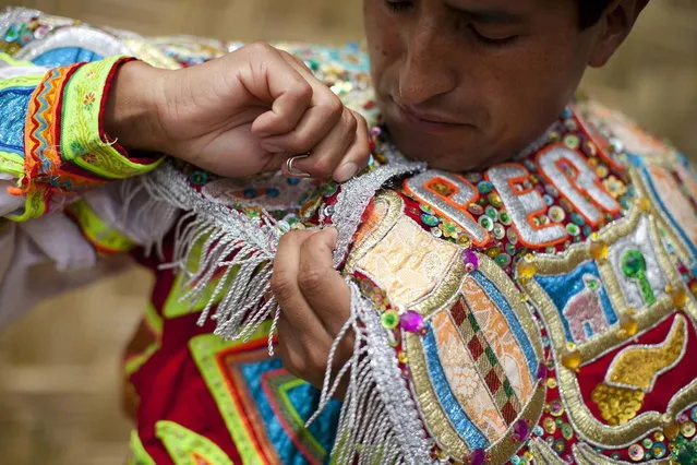 A "scissors" dancer prepares his suit before performing in a national scissors dance competition in the outskirts of Lima December 1, 2013. The Danza de las tijeras, or scissors dance, is a traditional dance from the Peruvian southern region of the Andes, in which two or more performers take turns dancing while accompanied with music from a harp and a violin. Dancers would display various skills and moves, which include cutting the air with the use of a scissors. (Photo by Enrique Castro-Mendivil/Reuters)