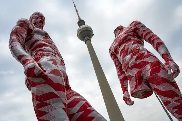 Mannequins wrapped in barrier tape stand in front of Berlin's landmark TV Tower on April 1, 2021, as part of German artist Dennis Josef Meseg's Corona Memorial called “It is Like it is”. The moving exhibition will be set up near various landmarks in the German capital over the next days. (Photo by John MacDougall/AFP Photo)