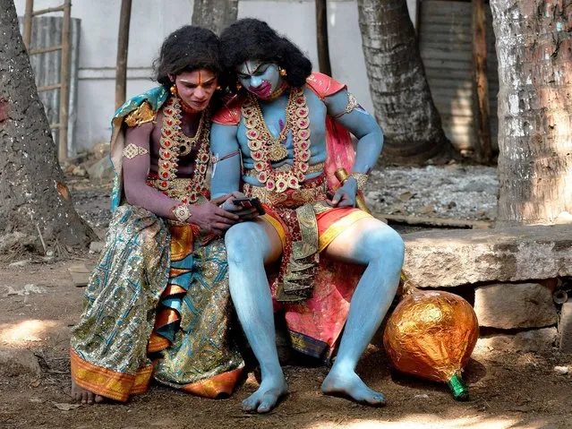 Indian artists dressed as Hindu monkey god Hanuman (R) and Lakshman watch a video on their mobile phone during Rama Navami festival celebrations at a temple in Bangalore on March 28, 2015. Rama Navami is a Hindu festival, celebrating the birth of the god Rama whom Hindus consider is the seventh incarnation of Lord Vishnu and is the oldest known Hindu god having human form. (Photo by Manjunath Kiran/AFP Photo)