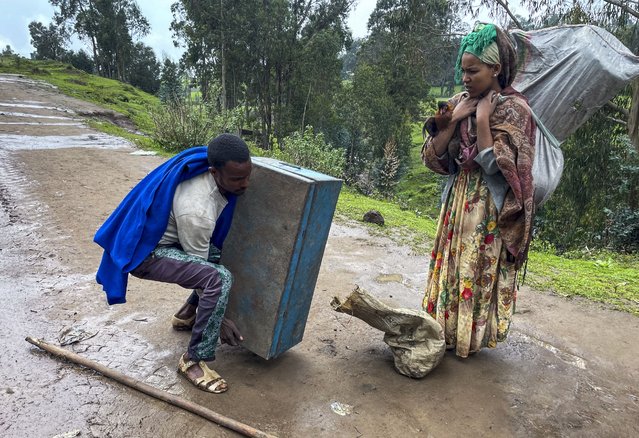 Senait Ambaw, right, who said her home had been destroyed by artillery, leaves by foot on a path near the village of Chenna Teklehaymanot, in the Amhara region of northern Ethiopia Thursday, September 9, 2021. (Photo by AP Photo/Stringer)
