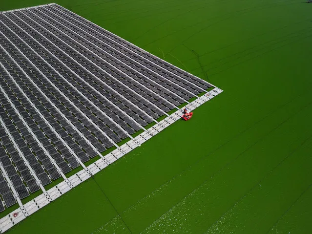 An aerial view shows workers from Nofar Energy installing solar panels on a water reservoir outside of Kibbutz Or HaNer, Israel on June 19, 2023. (Photo by Amir Cohen/Reuters)