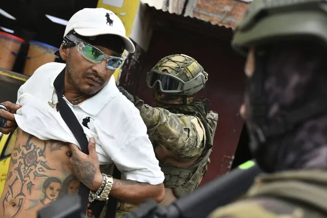 A soldier examines the back of a man checking for gang related tattoos, during a stop and frisk operation in Portoviejo, Ecuador, Thursday, January 11, 2024. President Daniel Noboa decreed Monday a national state of emergency due to a crime wave tied to drug trafficking gangs. (Photo by Ariel Ochoa/AP Photo)