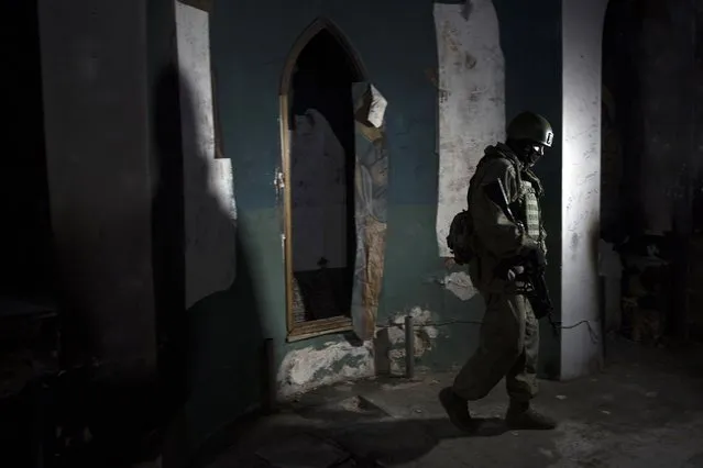 A Russian soldier, who escorted a group of journalists, walks inside a Greek Orthodox church in Maaloula, Syria, Thursday, March 3, 2016. Its historic churches pillaged by jihadis and buildings riddled with shrapnel, this ancient Christian town north of Damascus still bears the scars of fierce fighting that devastated it two years ago. (Photo by Pavel Golovkin/AP Photo)