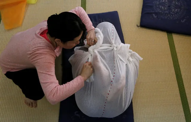 Participants perform Otonamaki, which translates as “adult wrapping”, a new form of therapy where people are wrapped in large swaddling cloth to alleviate posture problems and stiffness, at a session in Asaka, Saitama prefecture, Japan, February 4, 2017. (Photo by Toru Hanai/Reuters)