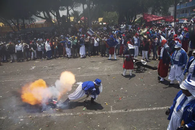 People look on as local residents dressed as French soldiers fire a canon during a reenactment of the battle of Puebla in which Zacapoaxtla Indians fought the French Army, during Cinco de Mayo celebrations in the Penon de los Banos neighborhood of Mexico City, Tuesday, May 5, 2015. (Photo by Rebecca Blackwell/AP Photo)