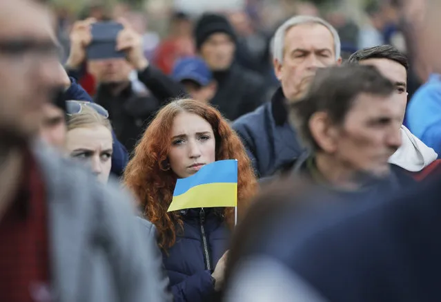 A woman holds an Ukrainian flag as protesters gather to march to the Olympic stadium ahead of debates between two candidates in the weekend presidential run-off in Kiev, Ukraine, Friday, April 19, 2019. Friday is the last official day of election canvassing in Ukraine as all presidential candidates and their campaigns will be barred from campaigning on Saturday, the day before the vote. (Photo by Vadim Ghirda/AP Photo)