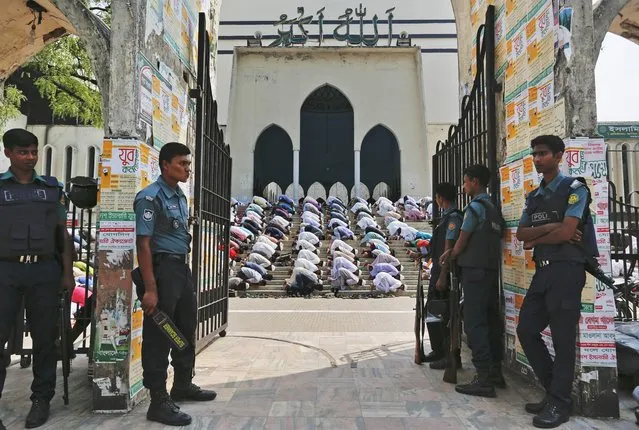Bangladeshi policemen stand guard outside Bangladesh national mosque as members of various Islamic political groups and other Muslims attend Friday prayers before a protest in Dhaka, Bangladesh, Friday, March 25, 2016. Thousands of Muslim devotees have rallied in Bangladesh's capital to denounce a court petition seeking to remove Islam as state religion in the Muslim-majority South Asian nation which is ruled by secular laws. (Photo by A.M. Ahad/AP Photo)