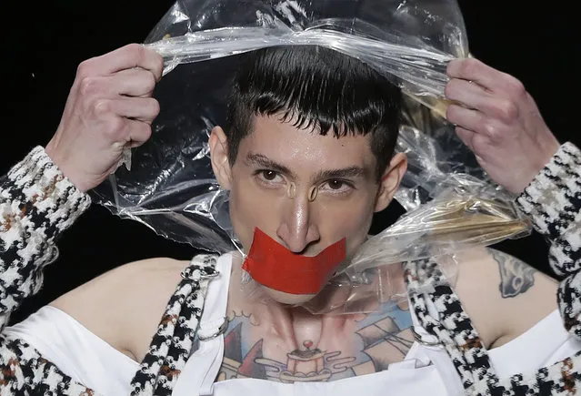 In this April 24, 2019 photo, a model tears a plastic bag from his head, as he wears a creation from the João Pimenta collection during Sao Paulo Fashion Week in Sao Paulo, Brazil. (Photo by Andre Penner/AP Photo)
