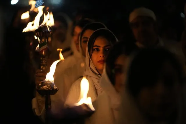 Iranian Zoroastrian youth carry torches to set fire to a prepared pile of wood in a ceremony celebrating their ancient mid-winter Sadeh festival in outskirts of Tehran, Iran, Tuesday, January 30, 2024. Hundreds of Zoroastrian minorities gathered after sunset to mark their ancient feast, creation of fire, dating back to Iran's pre-Islamic past. (Photo by Vahid Salemi/AP Photo)
