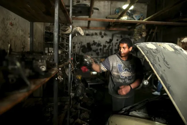 Palestinian boy Mohamoud Yazji, 16, who works as apprentice mechanic, repairs a car at a garage in Gaza City March 17, 2016. Yazji, whose father works as a tailor, earns 50 Shekels ($12.9) a week to help his father support their family. The boy, who quit school, hopes to own a garage in the future. (Photo by Mohammed Salem/Reuters)