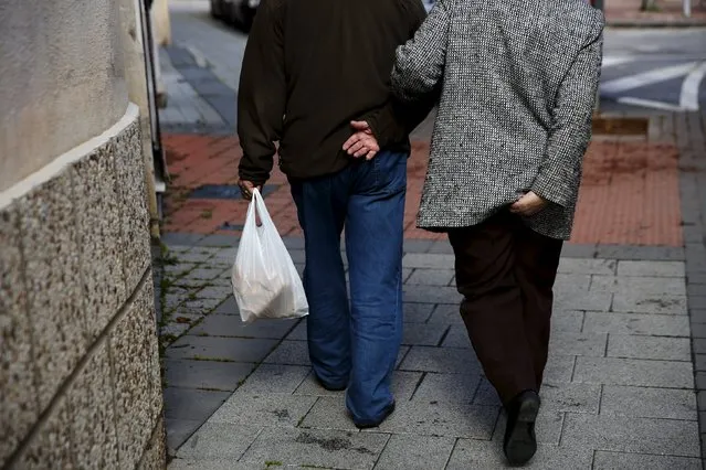 A couple walks together after buying bread in Alcazar de San Juan, Spain, April 5, 2016. (Photo by Susana Vera/Reuters)