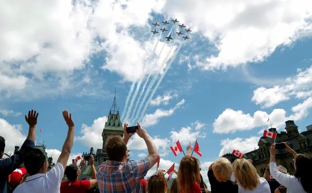 Canadians wave as the Snowbirds aerobatics team fly past during Canada Day festivities on Parliament Hill in Ottawa, Ontario, Canada on July 1, 2019. (Photo by Patrick Doyle/Reuters)