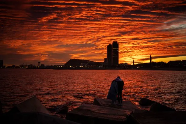 A couple watch as the sun sets from a breakwater in Barcelona, Spain, Saturday, January 8, 2022. (Photo by Emilio Morenatti/AP Photo)