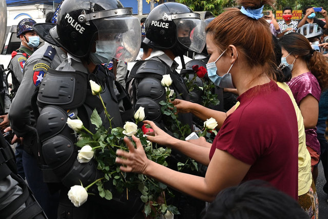 A protester gives bouquets of flowers to a line of riot police during a demonstration against the military coup in Yangon on February 6, 2021. (Photo by AFP Photo/Stringer)